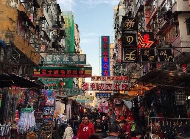 A busy Sham Shui Po market street under hanging shop signs