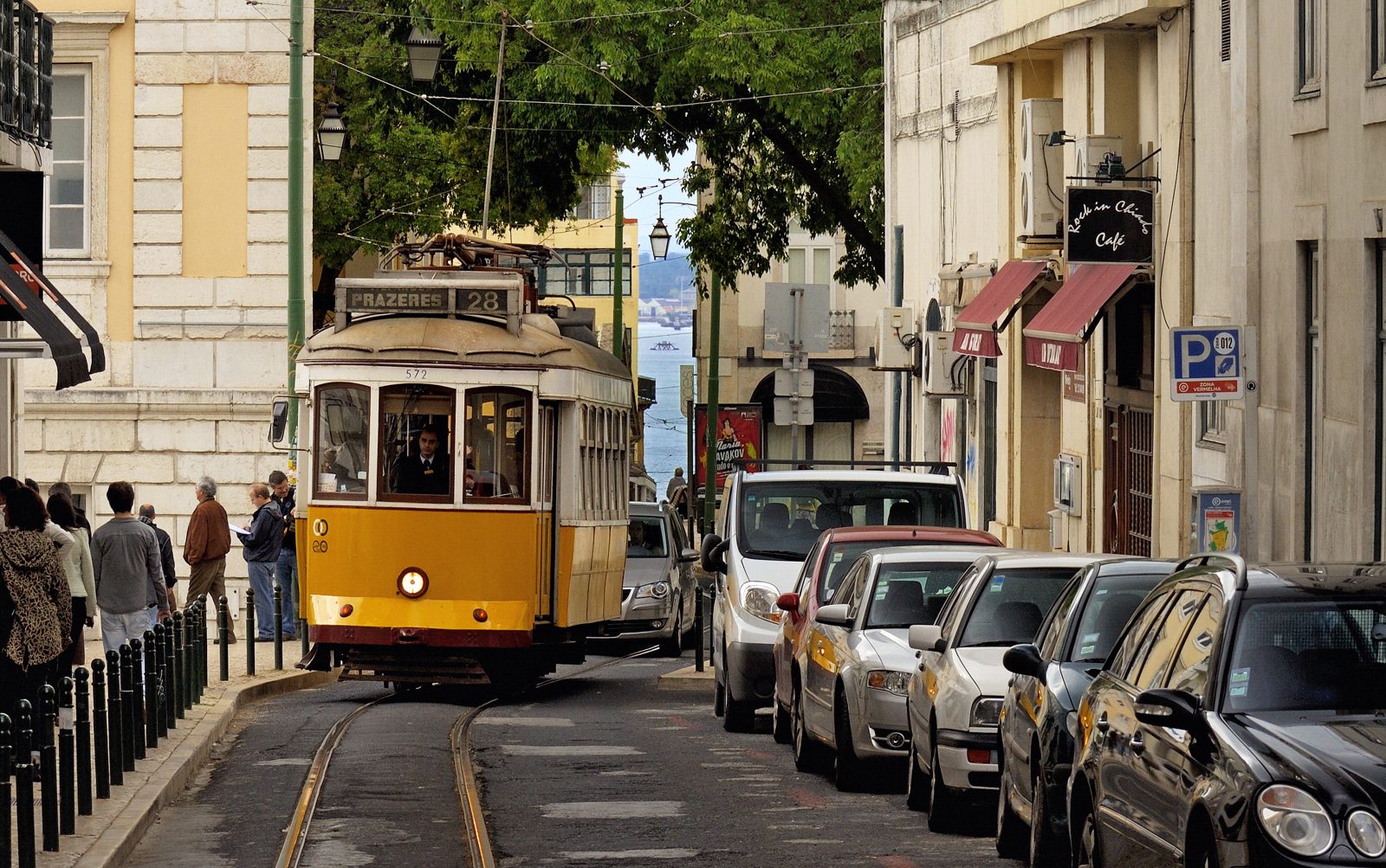 A yellow tram on the number 28 line climbing a cobbled Lisbon street.