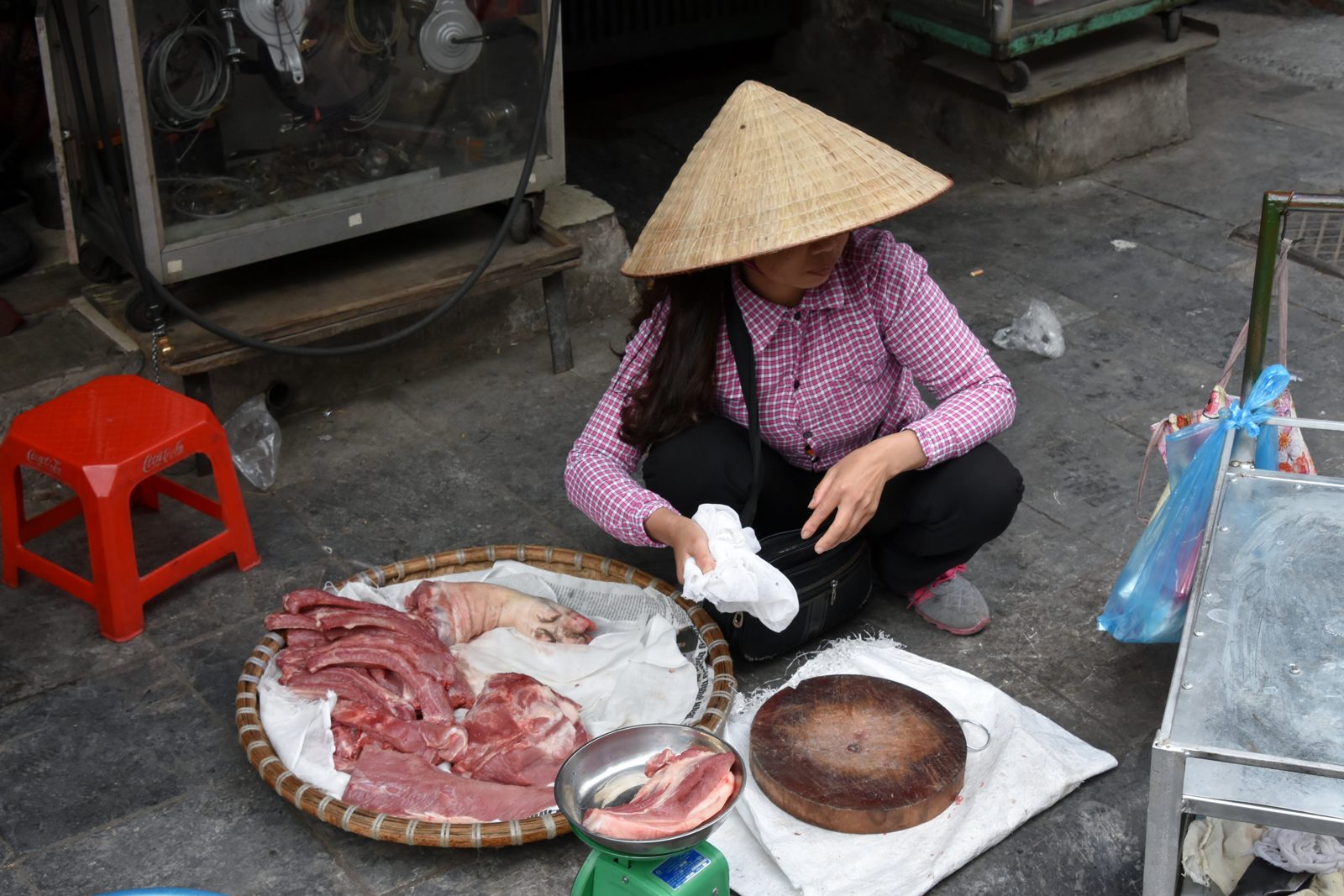 A narrow Old Quarter street in Hanoi lined with shopfronts, motorbikes and street vendors.