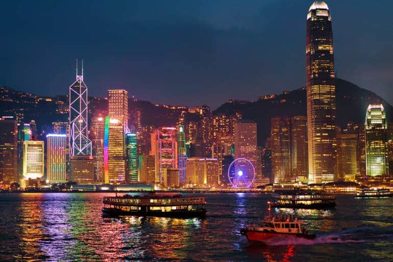 The lit Hong Kong Island skyline across the water at night, seen from the Kowloon waterfront