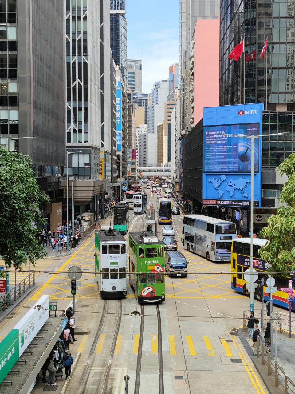 Double-decker trams on Des Voeux Road in Central, between the office towers