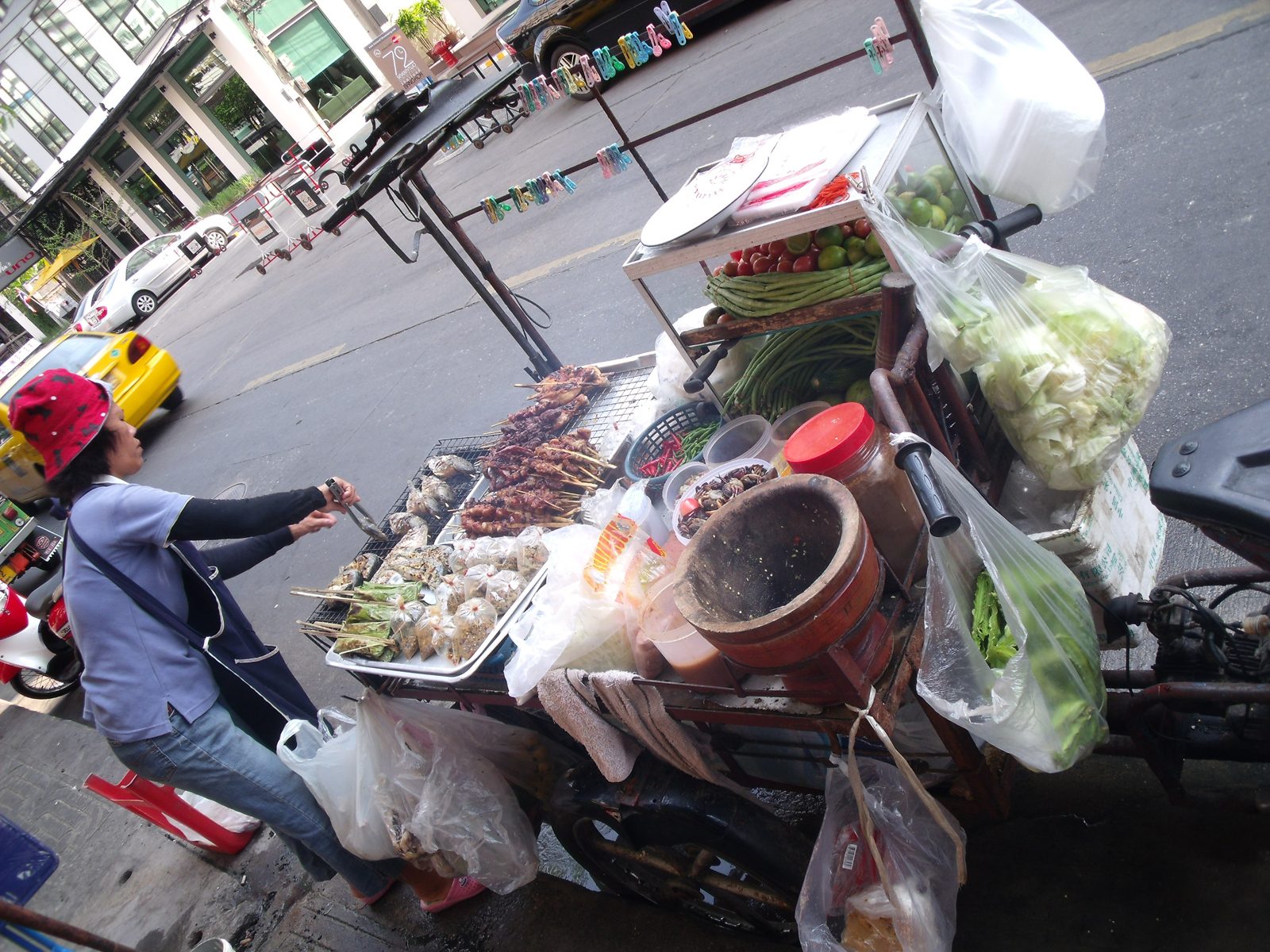 A street food vendor cooking at a cart on a Bangkok street.