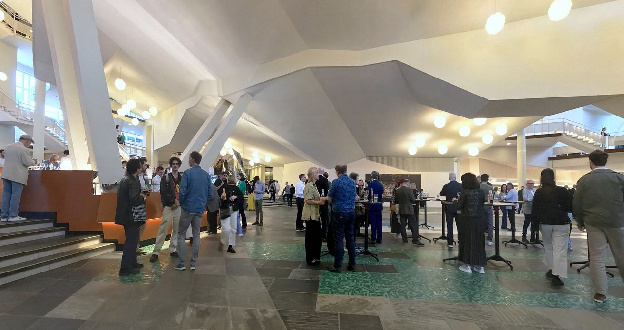 The foyer of the Berliner Philharmonie, with people standing among the concrete terraces and pale angular ceiling