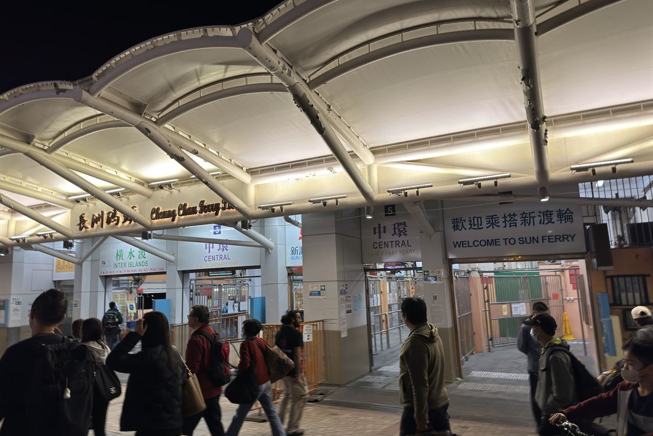Passengers at Cheung Chau ferry pier under signs for the Central ordinary and fast ferries
