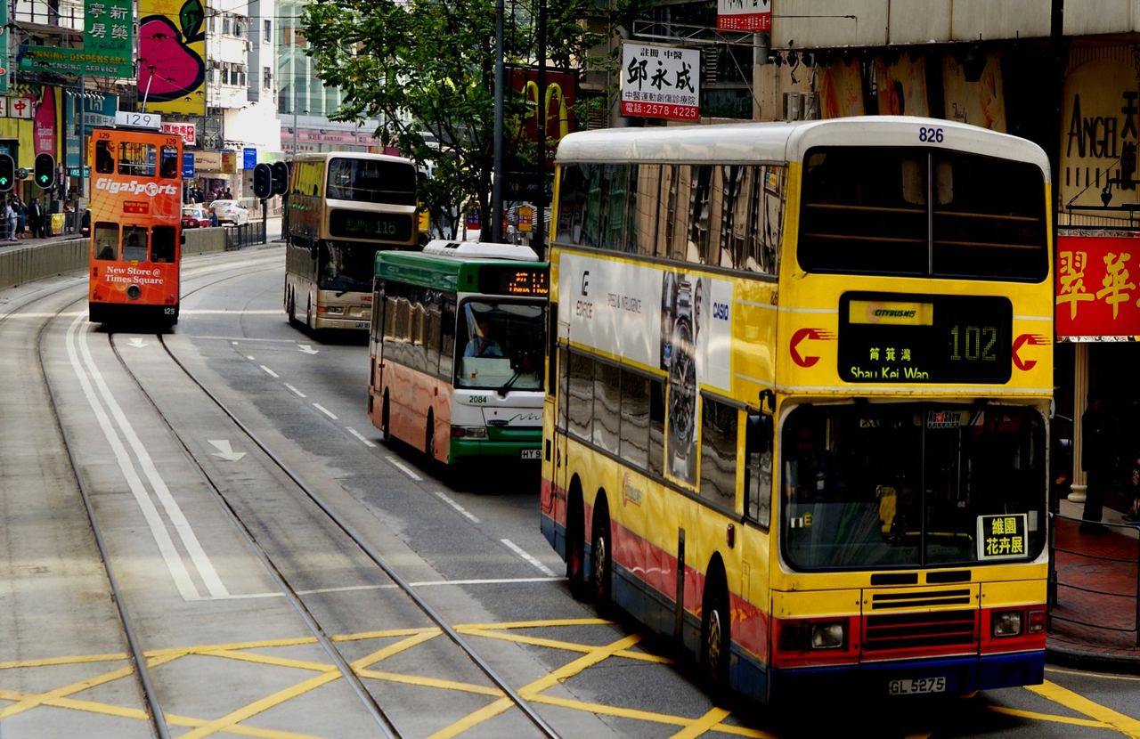 A tram and double-deck Citybus buses sharing a street on Hong Kong Island
