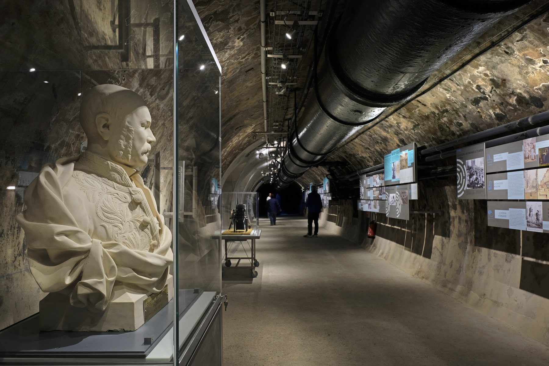 A vaulted gallery of the Paris sewer museum, running beside a live channel