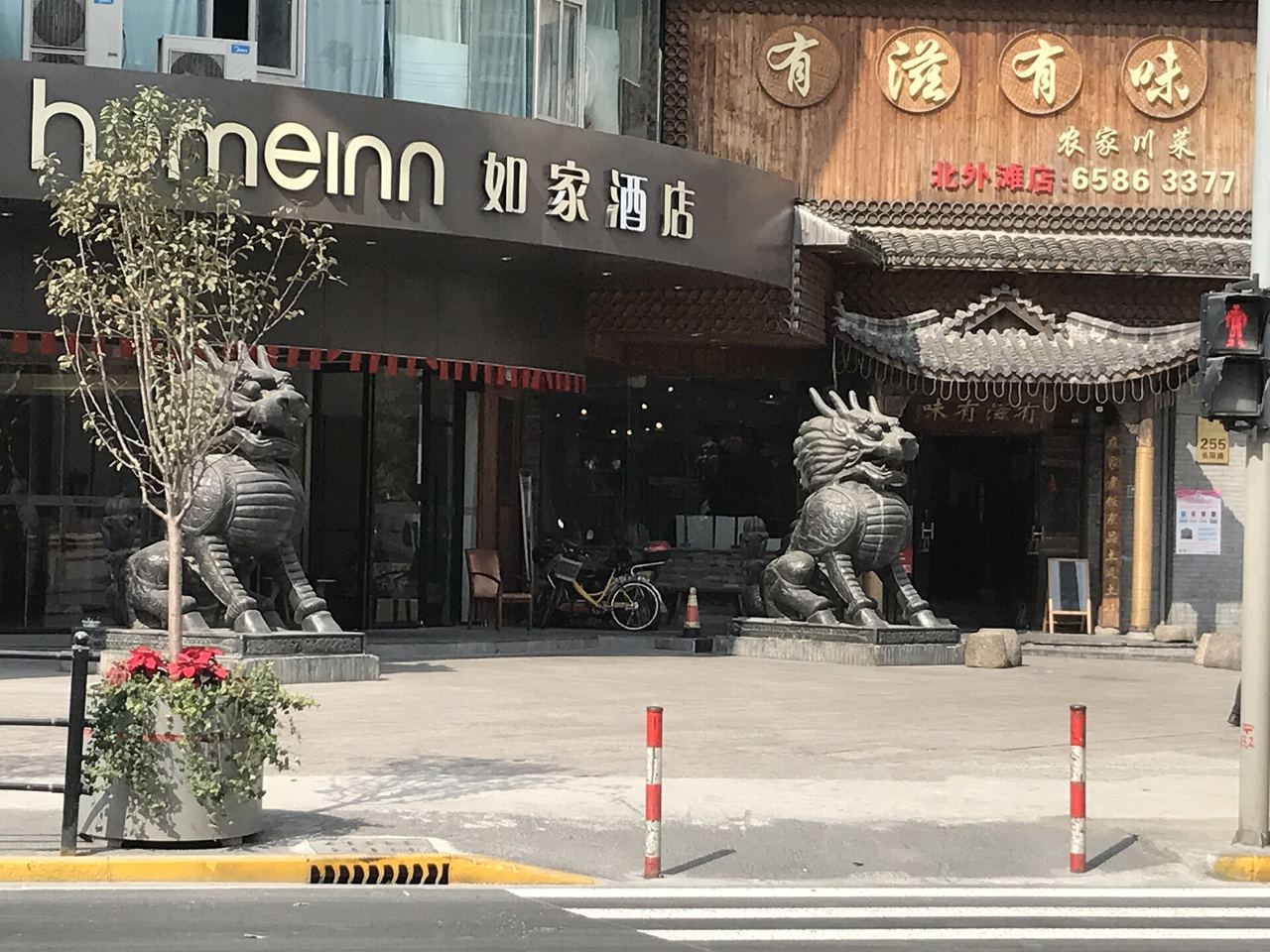 The street-level entrance of a Home Inn budget hotel in Shanghai's Hongkou district, flanked by decorative dragon statues