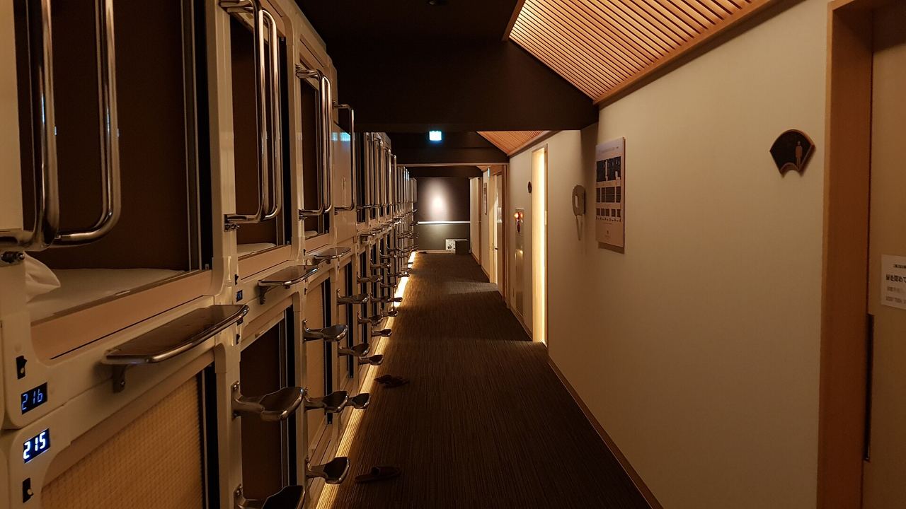 A hallway lined with stacked sleeping capsules in a Tokyo capsule hotel